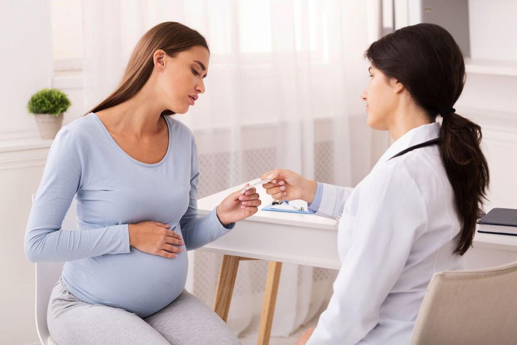 A pregnant woman in a doctor's office learning about thyroid medication.