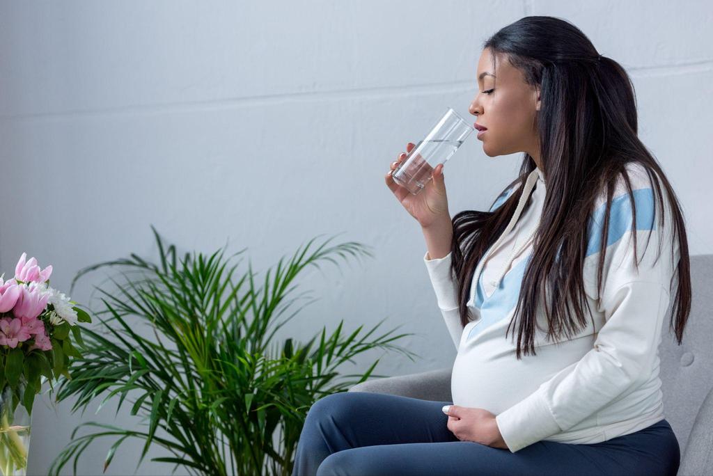 A woman in labour drinking water to stay hydrated and energised.