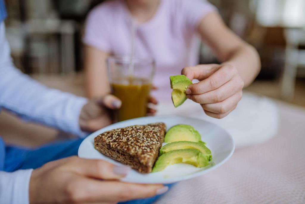 Pregnant woman enjoying avocado toast or a bowl of mixed nuts.